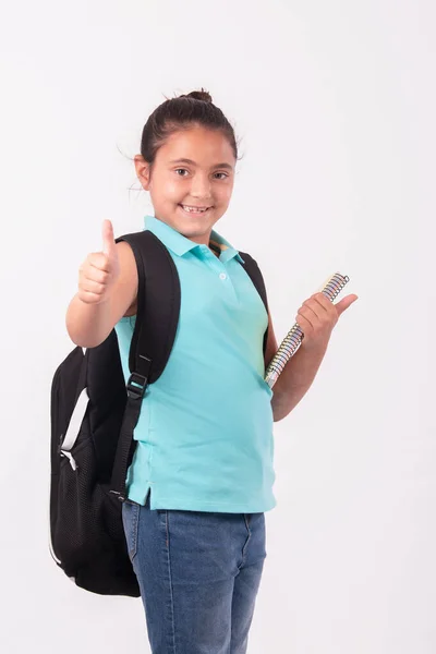 Piccola ragazza latina che fa un gesto pollice in su portando un grande zaino: concetto di scuola. — Foto Stock