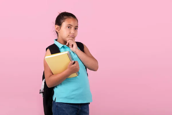 Pensive little latina dziewczyna niosąca plecak i notatnik: Szkoła i koncepcja wyrażeń. — Zdjęcie stockowe