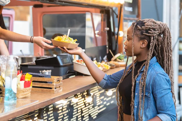 Afroamerikanerin erhält ein Fast-Food-Tablett mit Guacamole und Nachos: Selektiver Fokus lizenzfreie Stockfotos