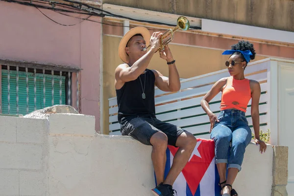 Mujer latina mirando a un hombre latino tocando una trompeta: enfoque selectivo. Concepto de música y diversidad. — Foto de Stock
