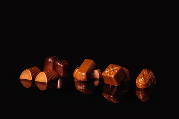 Close up of assorted chocolate sweets on a reflective surface — Stock Photo, Image