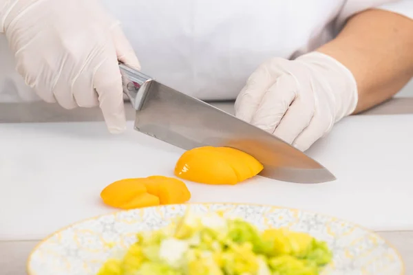 Close up of chef cutting a peach with a kitchen knife — Stock Photo, Image