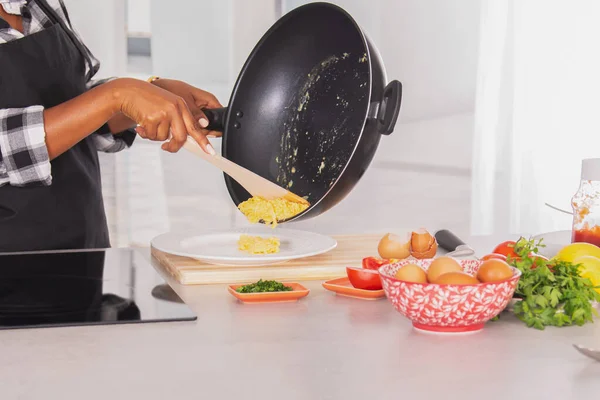 Αυγά ομελέτα χύνεται από ένα βαθύ τηγάνι σε ένα πιάτο Φωτογραφία Αρχείου
