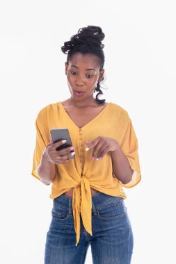 Afallamış Afro-Amerikan kadın beyaz arka planda cep telefonunu kullanıyor.