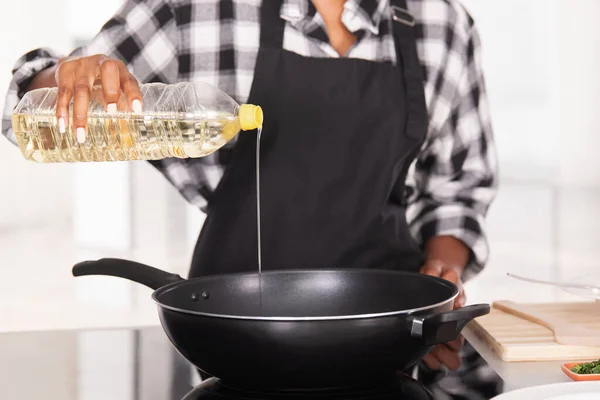 Close up of afro american woman pouring cooking oil into a deep frying pan — Stock Photo, Image