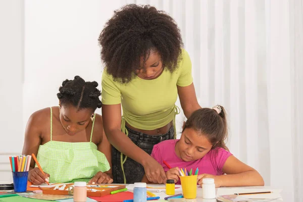 Dos maestros ayudando a la estudiante chica a dibujar con lápices de colores — Foto de Stock