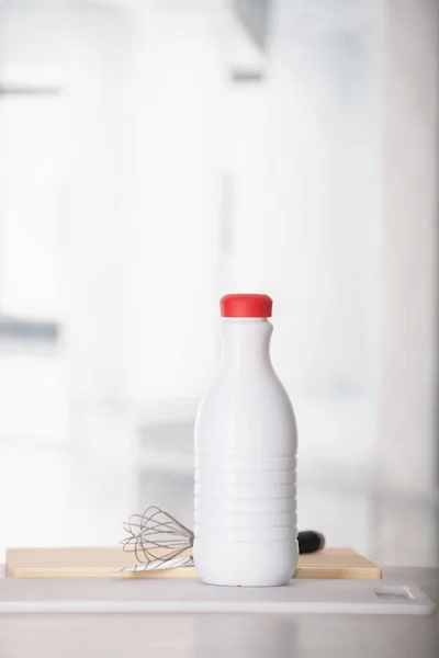 Botol susu dengan tangan kocokan di atas meja — Stok Foto