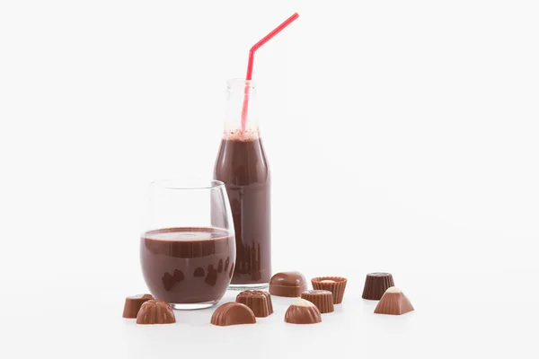 Tentant verre et bouteille de milk-shake au chocolat avec des bonbons au chocolat assortis : Mise au point sélective — Photo
