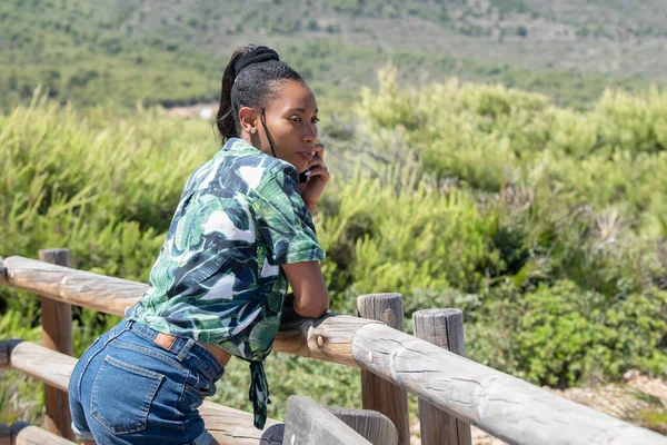 Афроамериканка, опирающаяся на деревянные перила, смотрит в сторону — стоковое фото