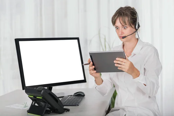 Shocked woman with headset in the office using digital tablet and computer screen is blank for copy space — Stock Photo, Image