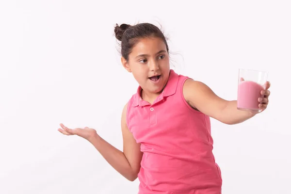 Niña sosteniendo un vaso con una bebida rosa con una cara asombrada Imagen de stock