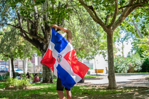 Latin férfi kezében Dominikai Köztársaság zászló szabadban — Stock Fotó
