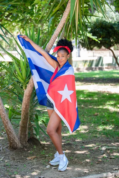 Mujer latina envuelta en bandera cubana sonriendo a la cámara —  Fotos de Stock