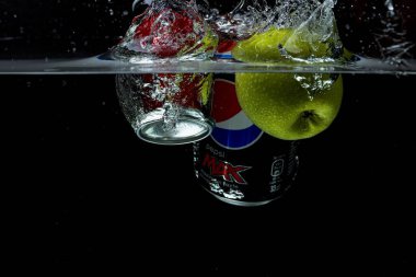 Yeşil elma, koka ve pepsi 'nin siyah arka planda suya düşüşünün yakın görüntüsü. Harika bir geçmişi var. 10.19.2020. Uppsala. İsveç.