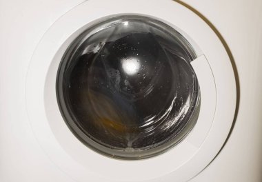 Çamaşır makinesinde dönen çamaşırların kapalı görüntüsü izole edilmiş. Ev aletleri kavramı.