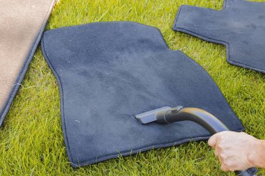 Süpürge süpürgesiyle yaz arabasının paspaslarını süpüren erkek eli görüntüsü. 