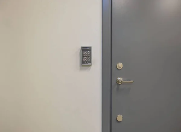 Close up view of grey metal door with digital code lock. Security concept.