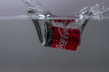 Gri arka planda suya düşen Coca Cola 'nın yakın görüntüsü. Harika bir geçmişi var. 10.19.2020. Uppsala. İsveç.
