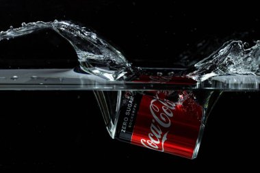 Siyah arka planda suya düşen Coca Cola 'nın yakın görüntüsü. Harika bir geçmişi var. 10.19.2020. Uppsala. İsveç.