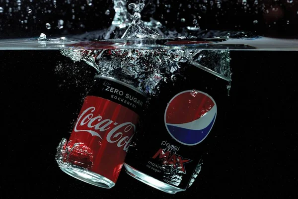 Koka ve pepsi 'nin siyah arka planda suya düşüşünün yakın görüntüsü. Harika bir geçmişi var. 10.19.2020. Uppsala. İsveç.