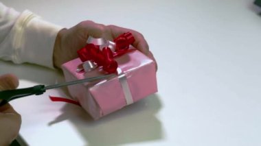 Erkeğin hediyeyi beyaz bantla kırmızı kağıtta açtığı yakın plan görüntüsü. Tatillerde. Noel zamanı. Yeni Yıl.