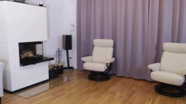 Modern oturma odasının güzel manzarası. Beyaz şömine, beyaz duvar arkasında açık renkli mobilyalar..