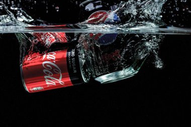Koka ve pepsi 'nin siyah arka planda suya düşüşünün yakın görüntüsü. Harika bir geçmişi var. 11.21.2020. Uppsala. İsveç.