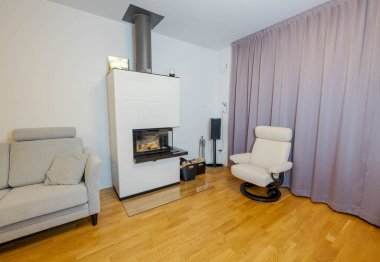 Modern oturma odasının güzel manzarası. Beyaz şömine, beyaz duvar arkasında açık renkli mobilyalar..