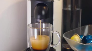 Kapsül kahve makinesinden cam fincana kahve görüntüsünü kapat. Güzel arka planlar.