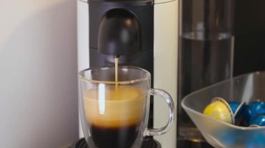 Kapsül kahve makinesinden cam fincana kahve görüntüsünü kapat. Güzel arka planlar.