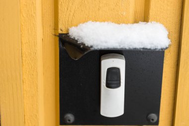 Elektrikli kapı zili düğmesinin üzerindeki karlı korumalı kapağı kapat. Kış mevsimi konsepti.