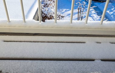 Arka planda karlı arka plan çalıları olan karlı balkon korkuluklarını kapatın. İsveç.