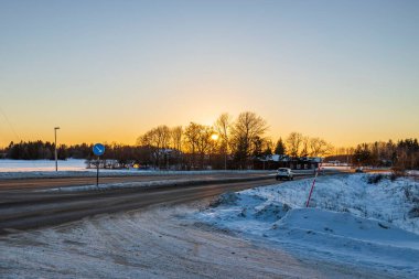 Güzel kış manzarası. Karlı kavşaklar ve orman ağaçlarının arkasında gün batımı. İsveç.