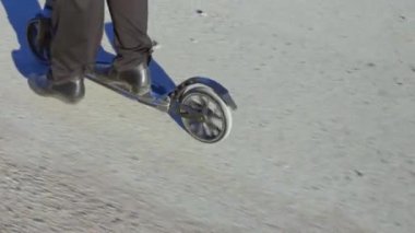 Tekmeli scooter 'ın üzerinde duran kadının yakın görüntüsü. İsveç.