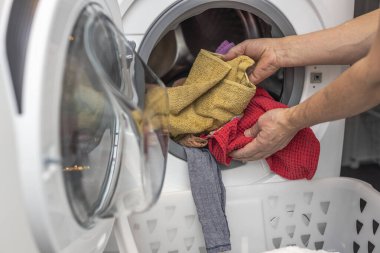 Çamaşırları çamaşır makinesine yükleyen adamın yakın görüntüsü. 