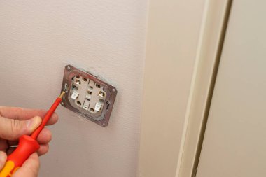 Elektrik teknisyeninin duvar lambasını tamir ederken ki görüntüsü. İnşaat elemanları konsepti oluşturuluyor. 