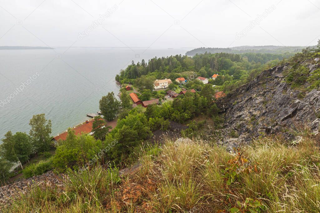 A wonderful view from mountains to nature with a view of Baltic Sea. The tops of green forest trees against backdrop of a stormy sky on a cloudy summer day. Sweden.