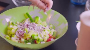 Salata kasesine eklenen kırmızı soğanın yakın görüntüsü. Sağlıklı gıda konsepti.