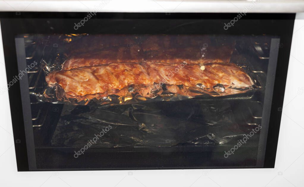 Close up view of pork ribs grilling process in stove. Food and health concept.