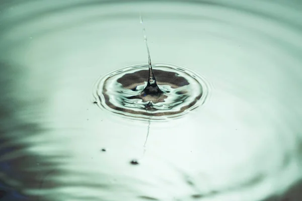 View of drops making circles on water surface isolated on background.