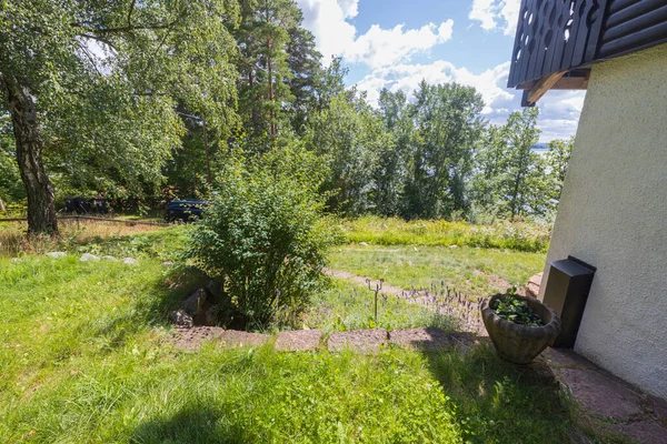 Beautiful nature landscape view. House wall on green trees and blue sky with white clouds background. Sweden.