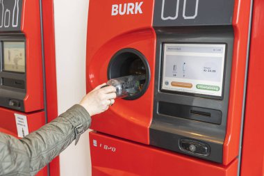 Kadının otomatik geri dönüşüm makinesine plastik şişe koyuşunu yakından izle. Avrupa. İsveç. Uppsala. 04.28.2021.