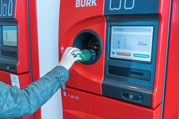 Otomatik geri dönüşüm makinesine metal konserve koyan bir kadının yakın görüntüsü. Avrupa. İsveç. Uppsala. 04.28.2021.