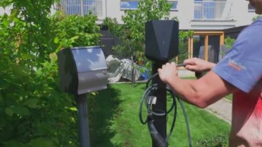 Close up view of man connecting charging cable to charging station for electric car. Sweden.  Uppsala. 