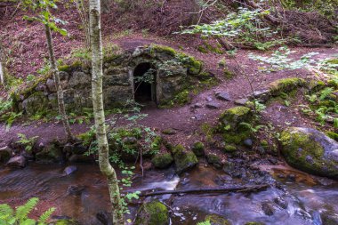 Güzel doğa manzarası. Kayalık arazideki terk edilmiş mağara ve su akıntısına giriş. İsveç.