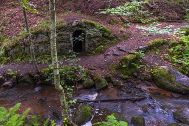 Güzel doğa manzarası. Kayalık arazideki terk edilmiş mağara ve su akıntısına giriş. İsveç.