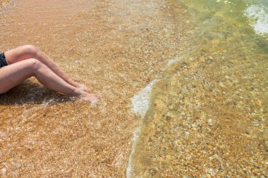 Kumsalda bacakları dalgalanan bir kadının görüntüsü. Yunanistan. 