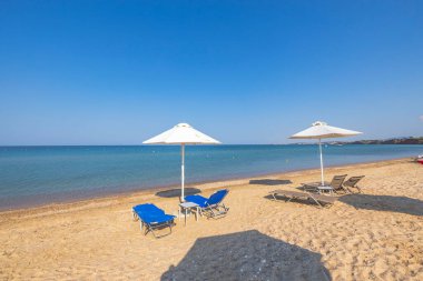 Landscape view of empty sunbeds under umbrellas on sandbeach. Greece.