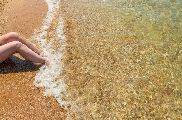 今後の波の中で足を砂のビーチに座って女性のビュー ギリシャ — ストック写真