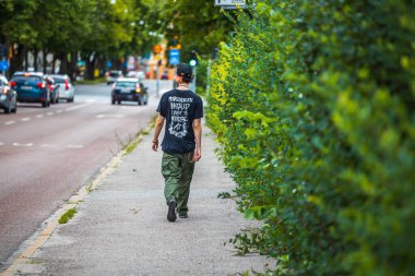 Yaz günü yolda yürüyen genç bir adam görüntüsü. İsveç. Uppsala. 08.25.2021.